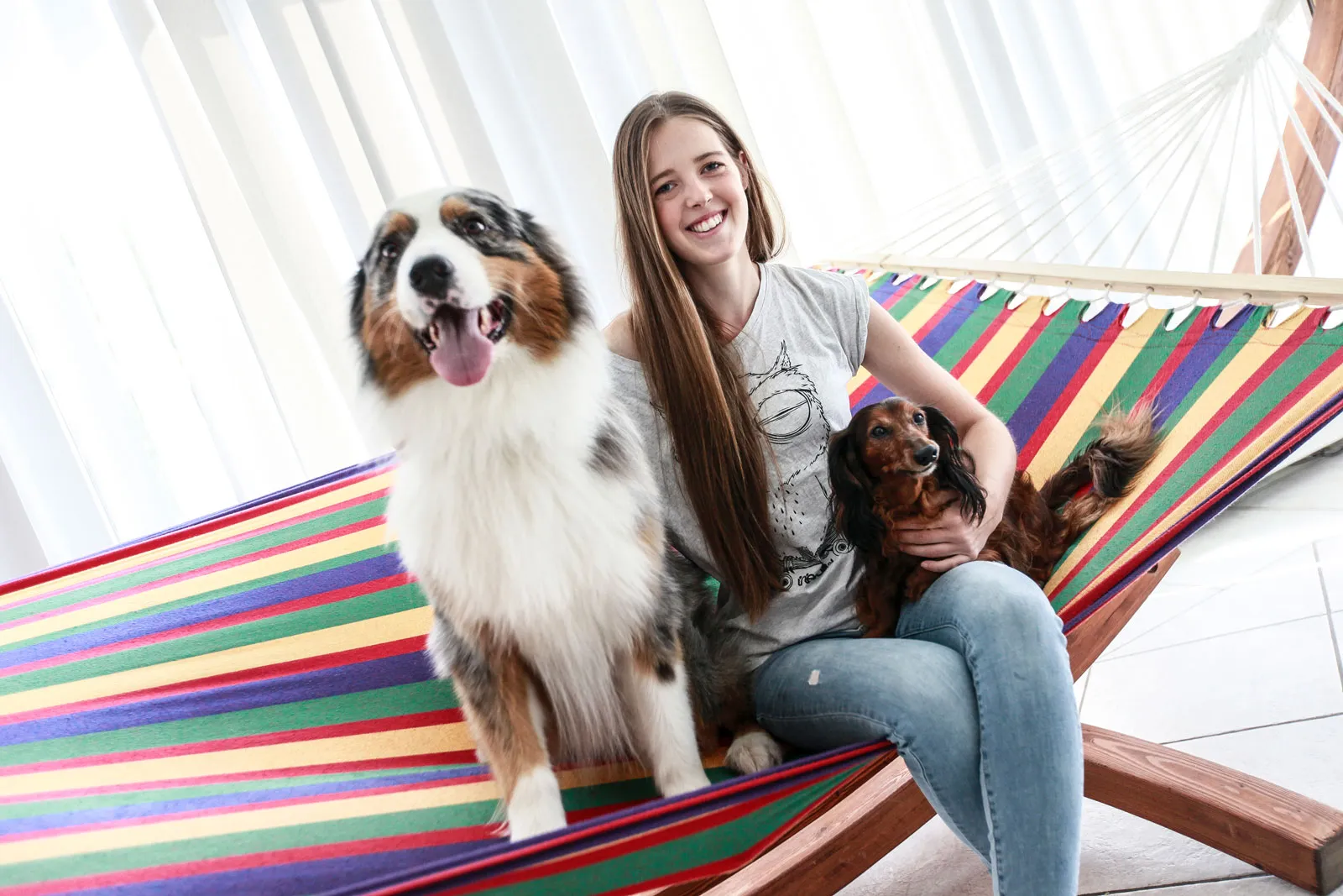 Anna Schmalenstroer mit einem Australian Shepherd und einem langhaarigen Dackel auf einer Hängematte